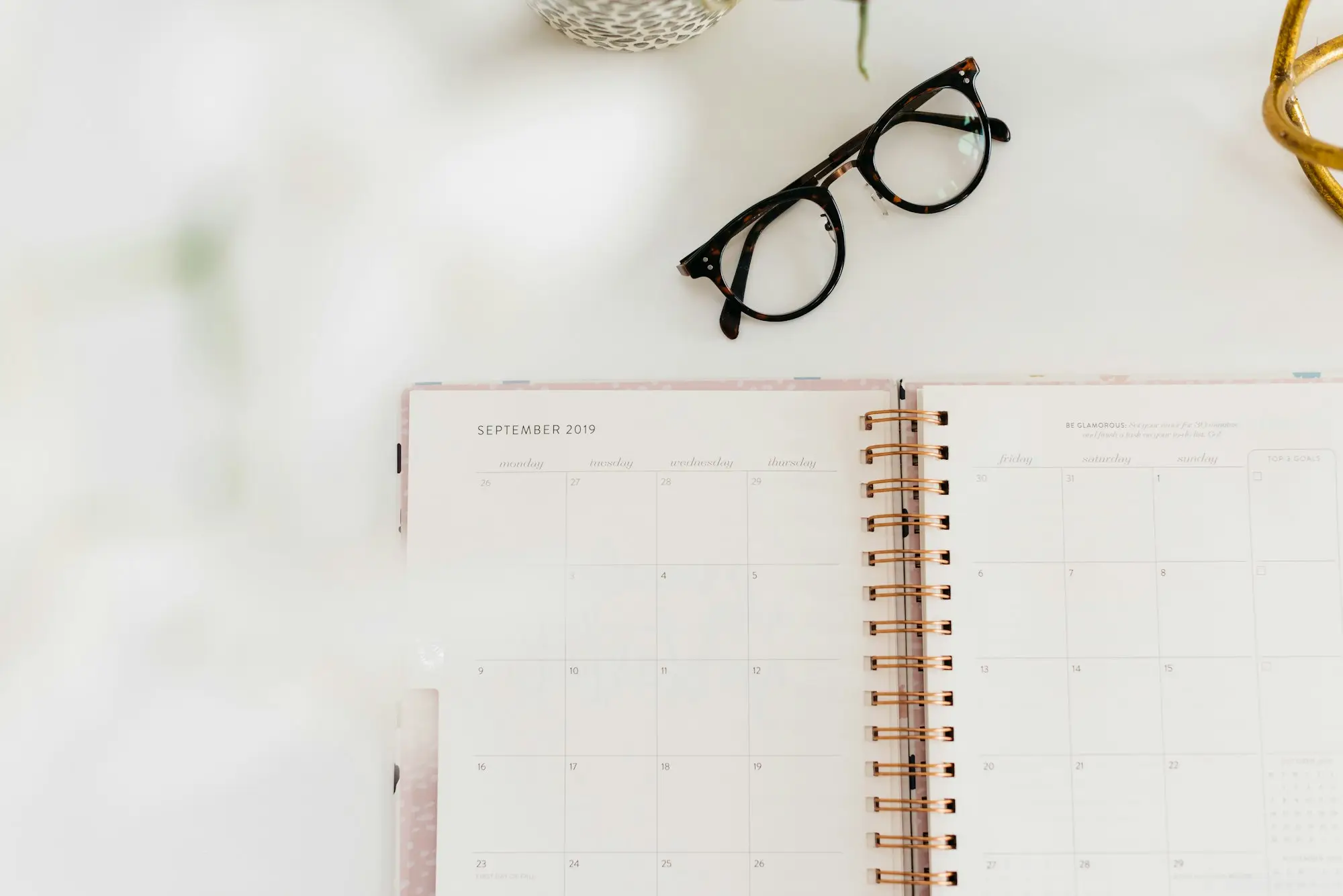 Open planner and glasses on a desk for mapping out the weeks ahead