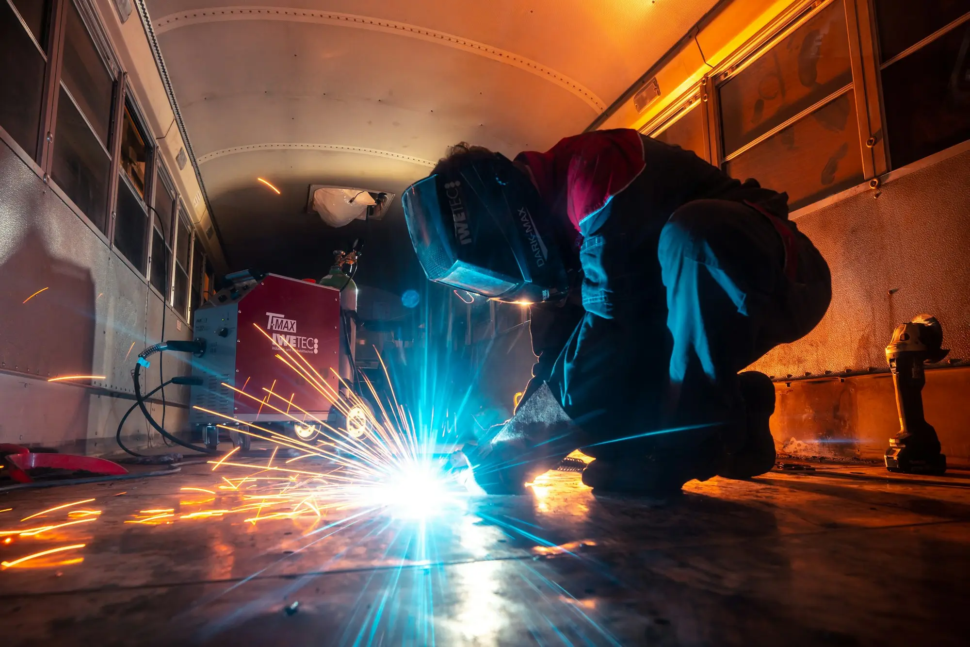 Welder working with sparks flying in a fabrication workshop