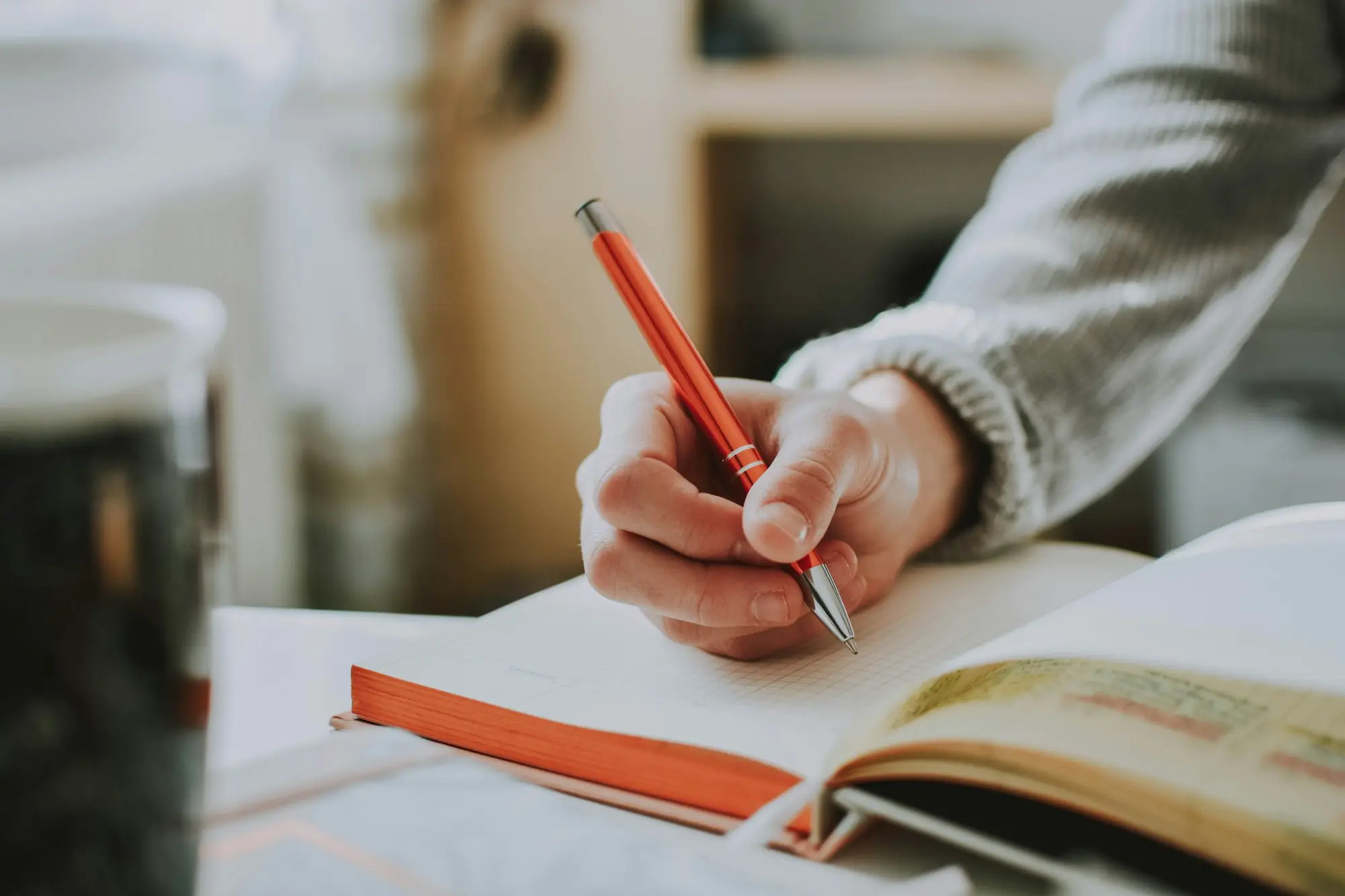 Person writing notes in a notebook while weighing up a decision